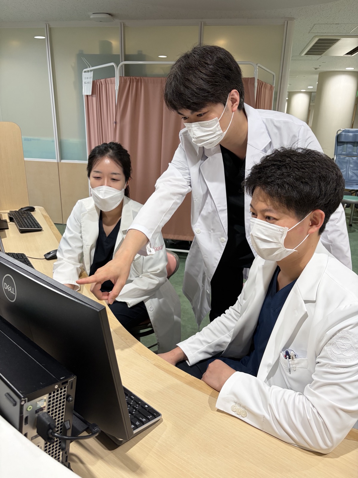 外来でモニターを囲んで症例を検討する研修医たち